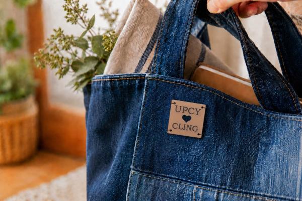 Vierkant lichtbruin cactusleren label met "UPCYCLING" en uitgestanst hart op een denim tas.