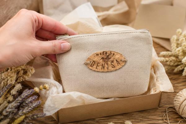 Ovaal kurklabel "made by Denisa" op een beige stoffen etui genaaid.