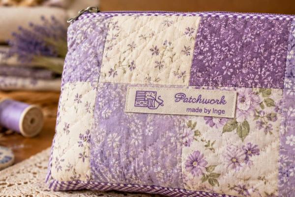 Naturelkleurig katoenen label met paarse tekst op patchworktas