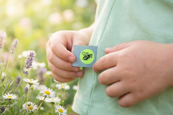 Lichtblauw vouwlabel met bijenmotief in de naad van kinderkleding